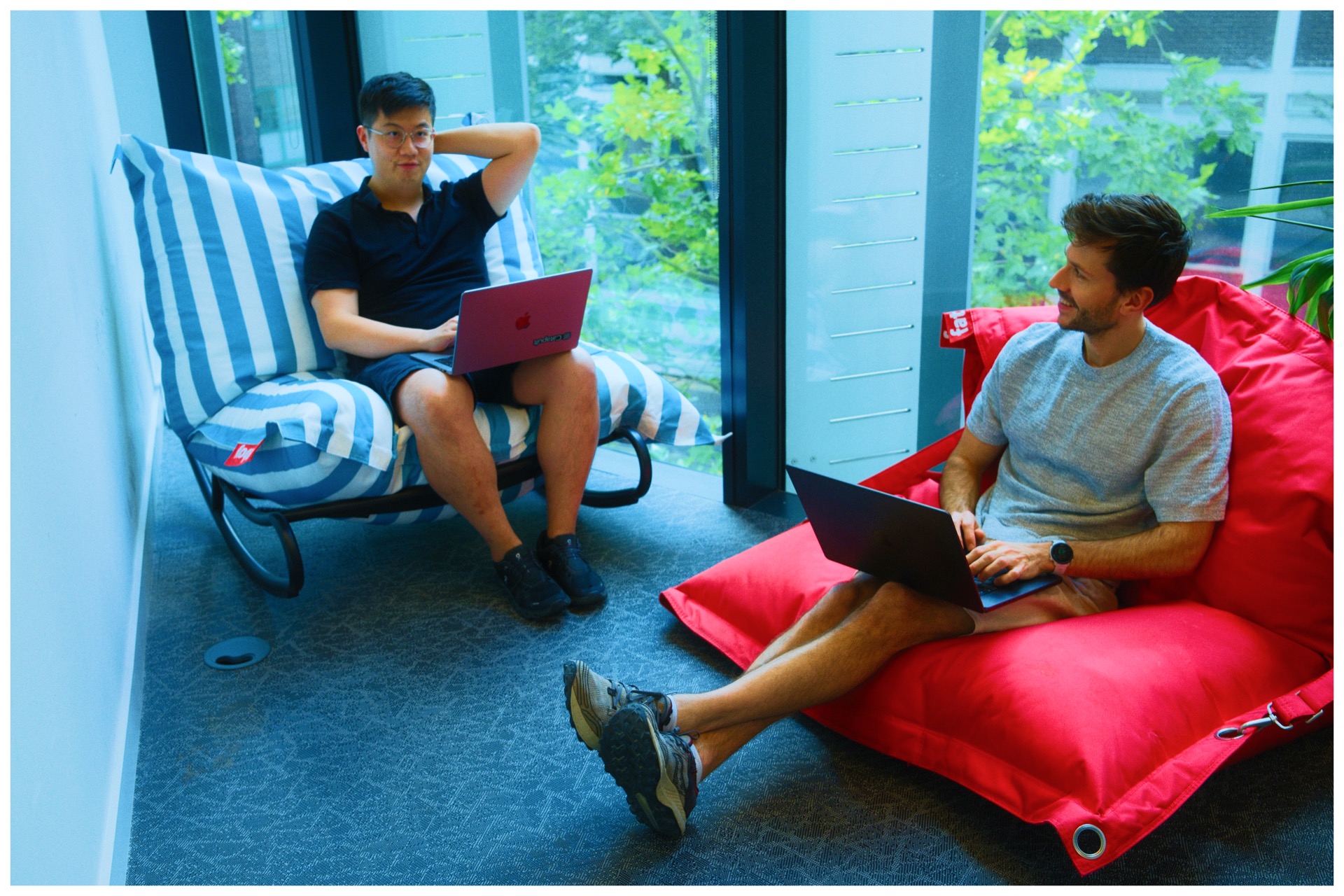 Two Catapult team members working with laptops in a lounge area
