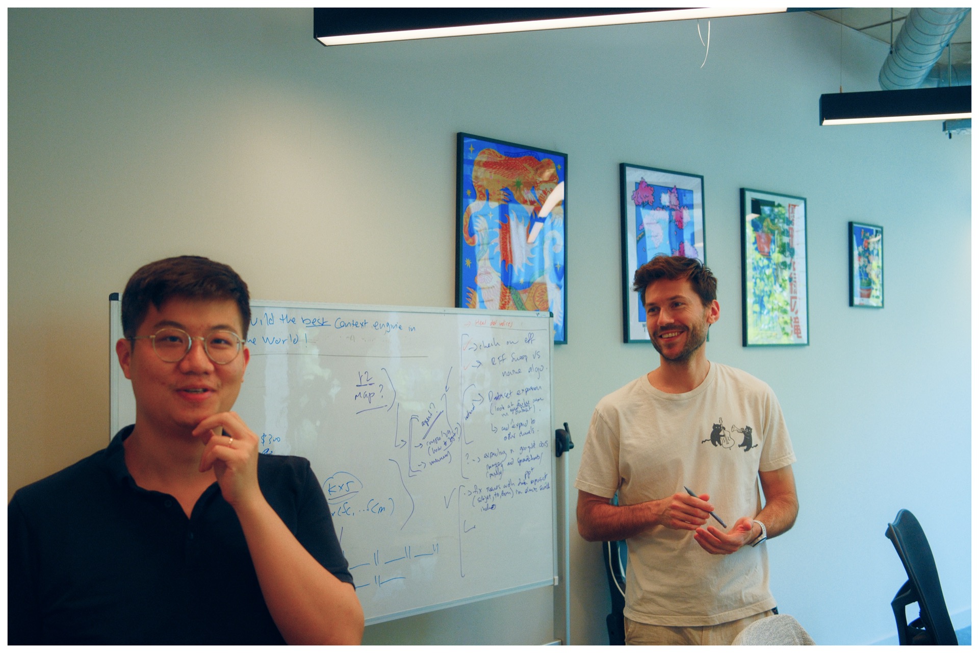 Two Catapult team members discussing ideas by a whiteboard